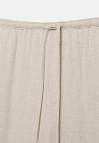Ceinture de pantalon en tissu de lin beige avec un cordon de serrage noué, centré en haut.