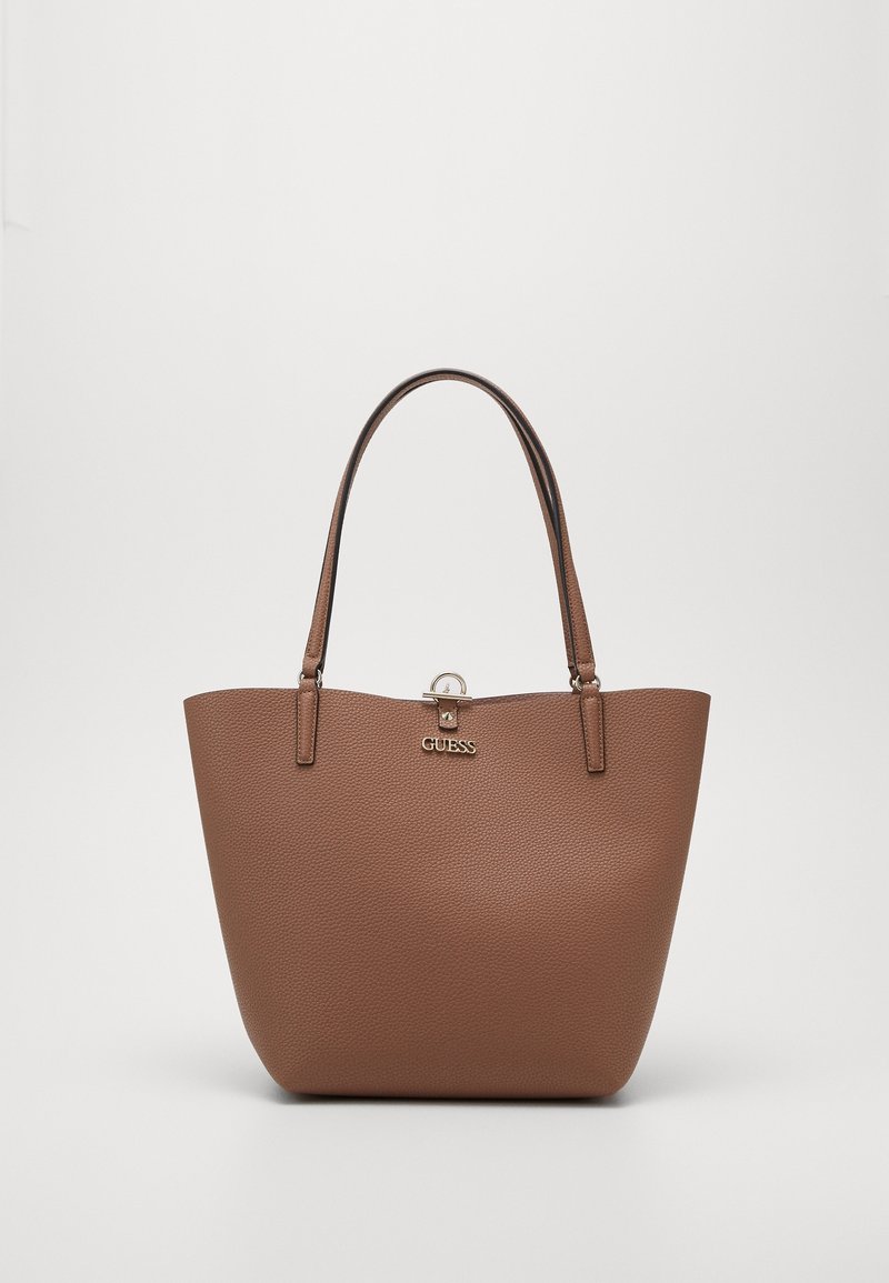 Sac fourre-tout en cuir brun granuleux avec deux sangles de portée, fermeture à fermoir sur le dessus et logo doré sur le devant. Intérieur lisse.