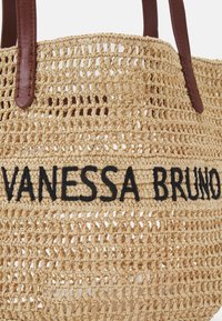 Tkaná slámová taška s hnědými koženými držadly a výšivkou "VANESSA BRUNO" v černé barvě na přední straně.
