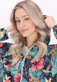 Jachetă cu glugă într-un model floral vibrant, având flori roz și portocalii pe un fundal întunecat, cu un fermoar și detalii de culoare albastru deschis.