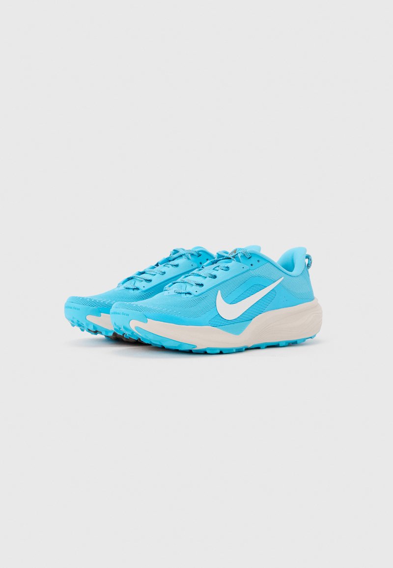 Par de zapatillas de correr Nike azul claro con el logo Swoosh blanco y suelas gruesas de color blanco hueso sobre un fondo liso gris claro.
