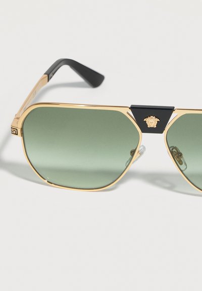 Γυαλιά ηλίου aviator με χρυσή κορνίζα και πράσινους φακούς, μαύρες λεπτομέρειες και λογότυπο Medusa στη γέφυρα.