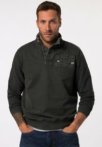 Sudadera gris oscura con cuello alto, cierre de cuarto de botón y tejido texturizado. Presenta un logo bordado en el pecho y puños de canalé.