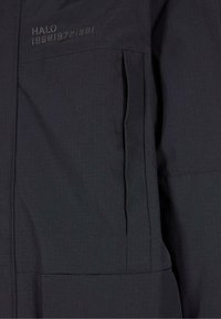 Mustat vuorelliset takit, joissa on teksturoitu ruudukkomalli, rinnassa oleva tasku, jossa on merkintä "HALO 196819721981" ja pystysuorat muotoilulinjat rakenteen vuoksi.