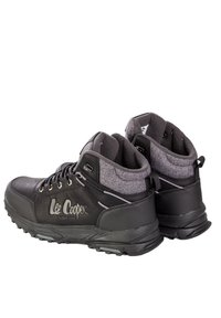 Czarne buty sportowe z teksturowaną tkaniną przy kołnierzu i szarymi akcentami. Buty mają solidną gumową podeszwę z widocznymi wzorami bieżnika.