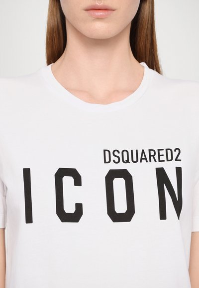 T-shirt en coton blanc avec un texte noir bold qui indique "DSQUARED2 ICON." Col rond et manches courtes avec une texture lisse.
