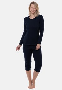 Maglietta a maniche lunghe navy con scollatura a girocollo e tasche, abbinata a pantaloni cropped. Tessuto morbido e liscio, vestibilità comoda e rilassata.