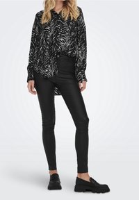 Zwart-wit gestreepte lange mouw shirt met een losse pasvorm, gecombineerd met strakke zwarte broek en zwarte instap schoenen. Glad textuur overal.