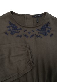 Olijfgroene blouse met verfijnde marineblauwe florale borduursels bij de halslijn en een gathersleeve detail. Zachte, gestructureerde stof.