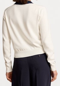 Pull en tricot couleur crème avec un col marine, bord-côte en bas et aux poignets, ayant une silhouette ajustée et une texture lisse.