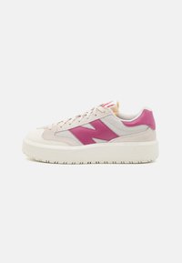 Zapatillas ligeras color beige claro con acentos sintéticos rosas, parte superior de malla y ante, suela de goma, punta redondeada y detalle del logo destacado en el lateral.