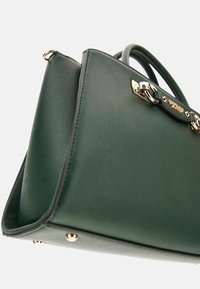 Borsa a tracolla in pelle sintetica verde con hardware dorato, forma strutturata, superficie testurizzata e dettagli di cucitura accentuati.