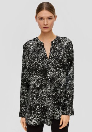 Blouse noire avec un motif blanc tacheté, col boutonné, manches longues et coupe ample. Fabriquée en tissu léger.