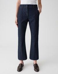 Pantalons en denim bleu foncé avec une taille haute, des jambes droites, des poches latérales et une couture visible. Portés avec des mocassins marron.