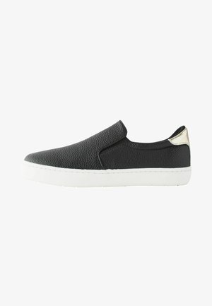 Black slip-on shoe with textured leather upper, white rubber sole, and silver accent at the heel. Minimalist design, no laces.