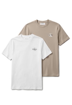To T-shirts med korte ærmer og rund halsudskæring, den ene hvid og den anden beige, begge med et lille Calvin Klein-logo på venstre bryst.