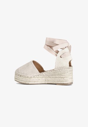 Wedge espadrille beige con tomaia in tessuto testurizzato, punta rotonda e soletta in juta intrecciata. Presenta cinturini in nastro incrociati alla caviglia.