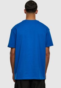 Camiseta de algodón azul con un corte relajado y cuello redondo, que presenta mangas cortas y una textura suave. Sin logotipos ni patrones visibles.