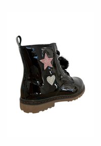 Botines negros de charol con parches de estrella rosa brillante y corazón plateado, un pom-pom negro y una suela de goma texturizada.