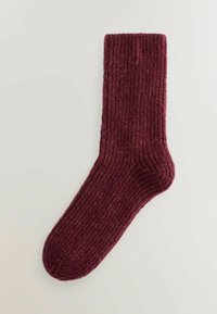 Burgunderfarbene gerippte Socke aus einem strukturierten Stoff, mit einem kontrastierenden goldenen Faden, der durch das Material gewoben ist.