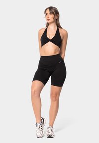 Top sportivo nero corto con collo all'americana e dettaglio a torsione, abbinato a pantaloni da ciclismo neri a vita alta; entrambi realizzati in tessuto elasticizzato.