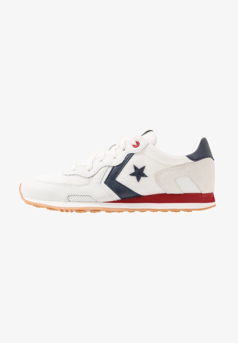 Sneaker bianca con accenti blu navy e dettagli rossi. Presenta una superficie testurizzata, logo a stella e suola in gomma con motivo antiscivolo.