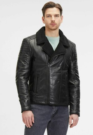 Veste en cuir noir avec un col en shearling, fermeture éclair et accents matelassés sur les épaules. Comprend deux poches zippées à l'avant et une texture lisse.