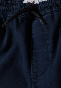 Joggers en coton bleu marine avec une taille élastique, fermeture à cordon et une poche latérale avec une texture lisse.