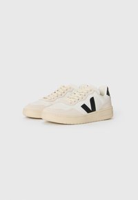 Sneaker con una combinazione di colori crema e nero, caratterizzati da una tomaia in pelle liscia, design con lacci, punta testurizzata e suola in gomma.