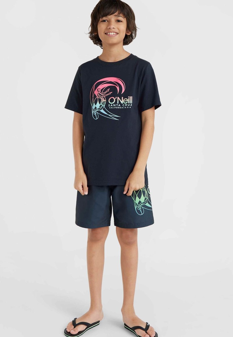 Marinblå t-shirt med kort ärm och färggrafik samt logotyp på bröstet, i kombination med mörka shorts med grafisk design. Svarta flip-flops.