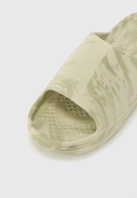 Sandale slip-on de culoare verde deschis, cu un finisaj marmorat, vârf deschis lat și o talpă interioară texturată, cu un model în grilă pentru aderență. Material durabil.