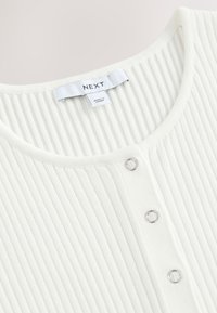Weißes, geripptes Strickoberteil mit rundem Ausschnitt, silbernen Knopfdetails und dem Markenetikett "NEXT" am Kragen.