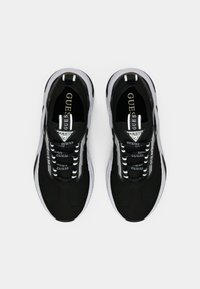 Μαύρα αθλητικά παπούτσια με επάνω μέρος από δίχτυ, κορδόνια λευκά και μαύρα, και υφή στη σόλα, με λογότυπο στη γλώσσα και διακοσμητικά στις πλευρές.