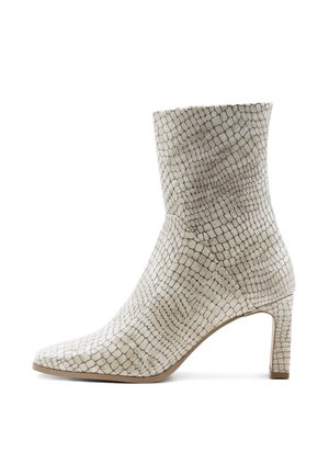 Stivaletto in pelle sintetica beige chiaro con un motivo a croco testurizzato. Punta affilata e tacco alto e sottile. Finitura liscia e opaca.