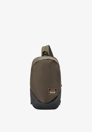 Kompaktowy, oliwkowozielony i czarny plecak na jedno ramię z jedną ramiączkiem i naszywką z napisem „Ochnik Riders Supply Custom Built” na przodzie.