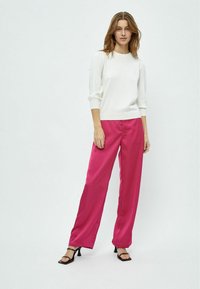 White knit sweater with three-quarter sleeves paired with bright pink satin wide-leg pants and black strappy heels, on a plain background.