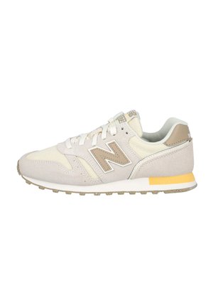 Zapatilla baja beige y crema con paneles de ante y malla, cierre de cordones, cuello acolchado y suela de goma con un detalle amarillo.