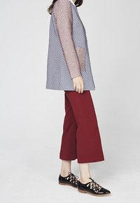 Translucent navy and white diamond-pattern blouse, paired with maroon wide-leg cropped pants and black patent leather lace-up shoes.