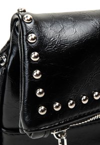 Borsa a mano nera in pelle sintetica con una superficie testurizzata, caratterizzata da borchie argentate lungo i bordi e una chiusura con zip nella parte inferiore.