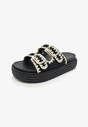 Sandale plateforme noire à glissière avec semelle épaisse tressée et deux brides noires réglables ornées de coutures beige en zigzag et de boucles dorées.