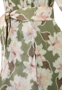Floral dress in lightweight, sheer fabric featuring soft pink and green tones. Includes a tied waist belt and pleated detailing.