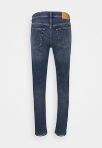 Mörkblå denimjeans med rak bendesign, med två bakfickor och en ljusbrun läderlapp på midjan.