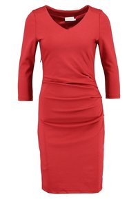 Abito rosso in tessuto liscio, con scollo a V, maniche a tre quarti e arricciature laterali per definire la forma. Silhouette semplice e aderente.