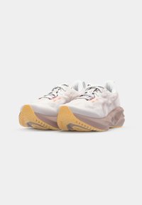 Zapatillas de running ligeras en un material texturizado blanco con acentos en gris y naranja. Cuentan con una suela acolchada y una suela de goma con tracción.