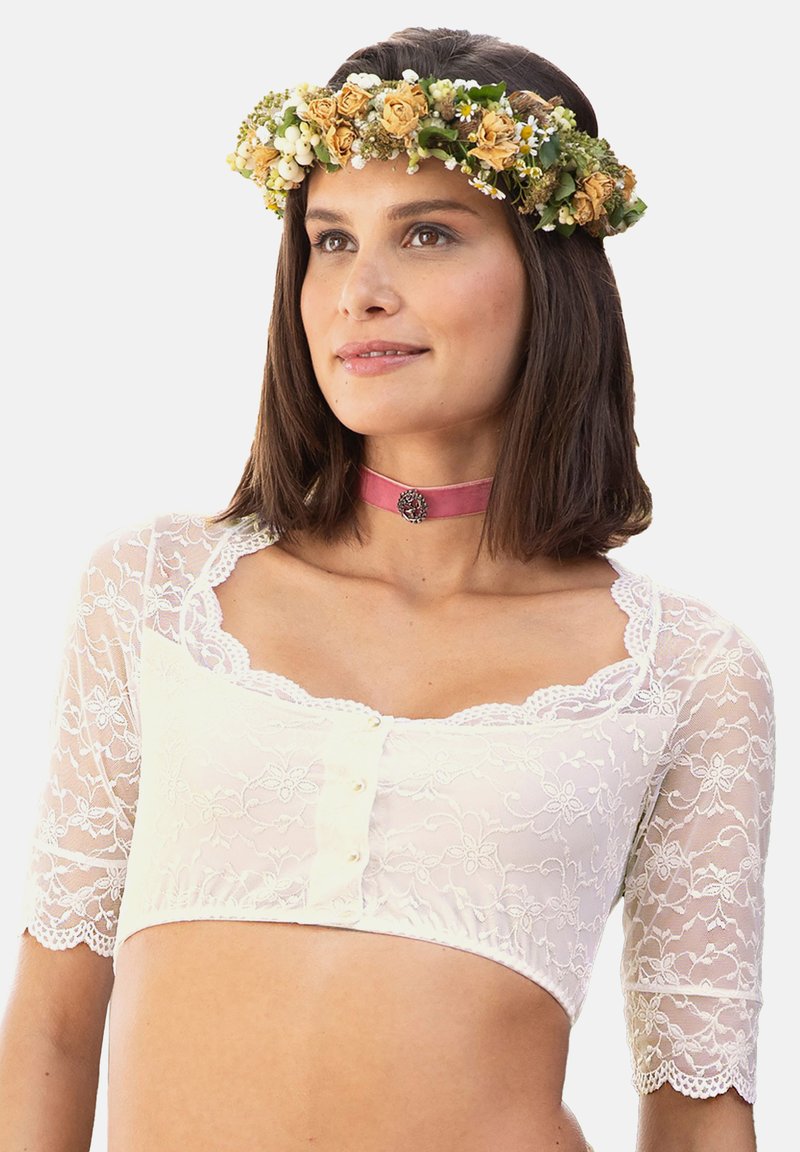 White lace crop top with short sleeves and floral embroidery. Features scalloped edges and front button closure. Paired with a floral crown.