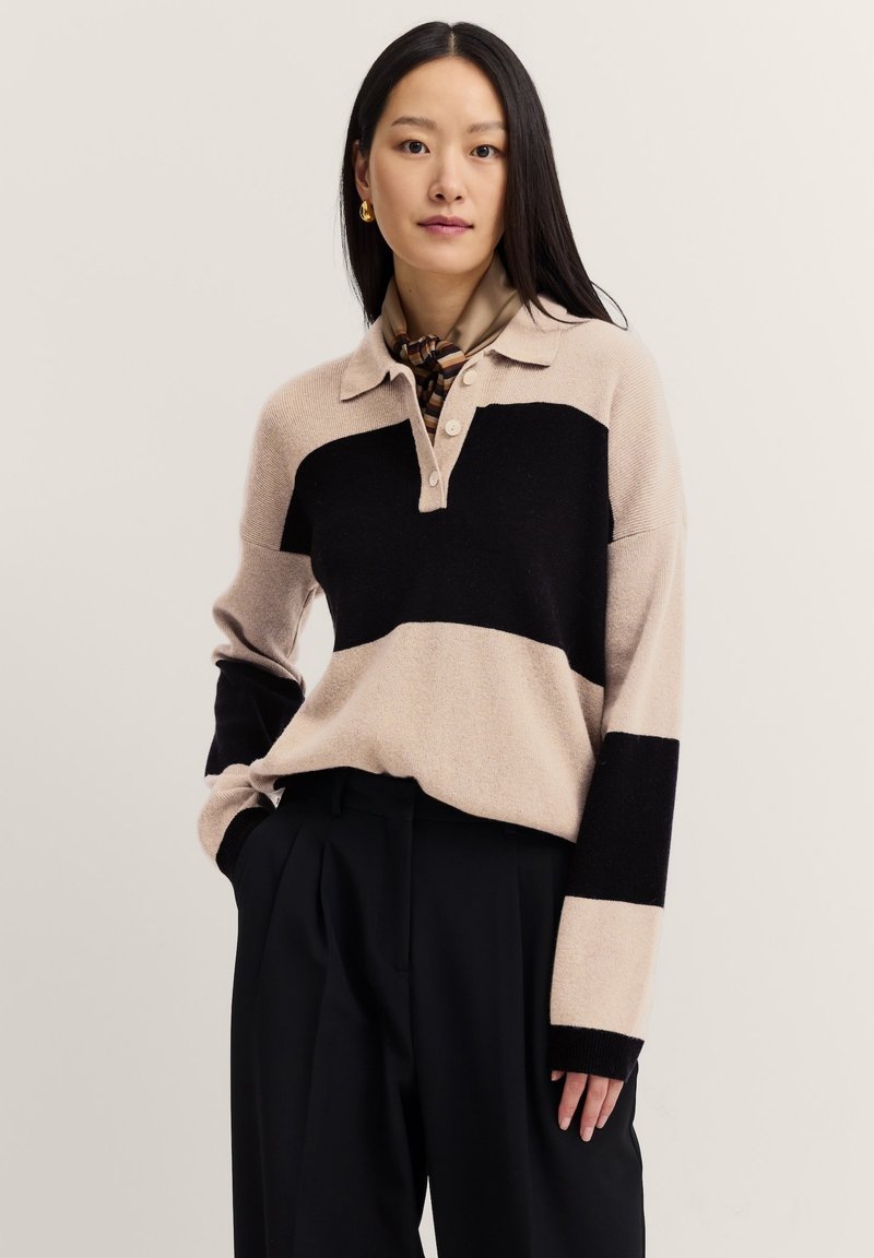 Beige und schwarz gestreifter Pullover mit Kragen und drei Knöpfen. Weicher Stoff mit langen Ärmeln und elastischen Bündchen.