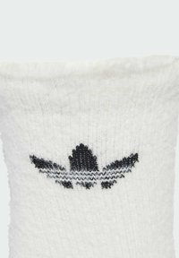 White sock with a soft texture; features a black embroidered logo with three stripes and a triangular outline.