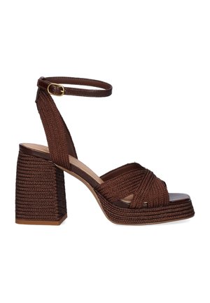 Sandalia marrón tejida con tacón bloque, tira en el tobillo y hebilla, con tiras cruzadas sobre los dedos abiertos y suela plataforma texturizada.