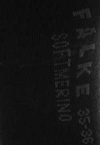 Schwarze, gestrickte Socken mit glatter Textur. Verfügen über graue, seitlich aufgedruckte Markenlogos und ein eng anliegendes, formbetontes Design.