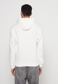 Weißer Hoodie aus weichem, strukturiertem Stoff, mit einer großen Kapuze, gerippten Bündchen und einem geraden Saum. Die Rückansicht zeigt keine Logos oder Muster.